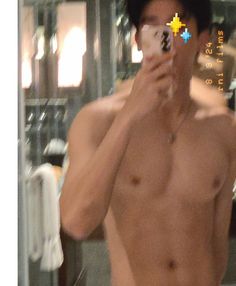 a shirtless man taking a selfie in front of a mirror with his cell phone