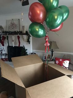 a bunch of balloons that are in a box on the floor near a christmas tree