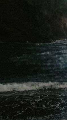 a man standing on top of a beach next to the ocean holding a surfboard