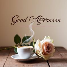 a cup of coffee and a rose on a wooden table with the words good afternoon