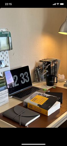 an open laptop computer sitting on top of a wooden desk next to a stack of books