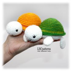 two crocheted turtle dolls sitting on top of each other in the palm of someone's hand