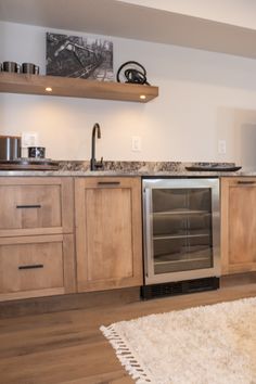 a kitchen with wooden cabinets and stainless steel appliance in the center, along with an area rug on the floor