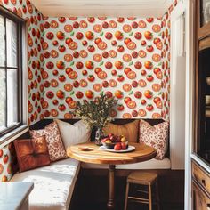 a small table with fruit on it in front of a wallpapered kitchen area