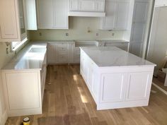 an empty kitchen with white cabinets and wood flooring in the process of remodeling