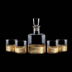 three glasses and a decanter are shown in front of a black background with gold dots