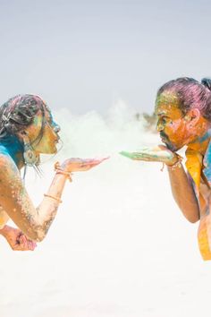 two people covered in colored powder holding plates