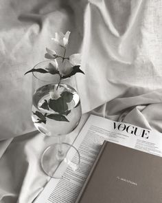 an open book sitting on top of a bed next to a vase filled with flowers