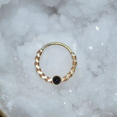 a gold ring with a black stone sits on top of some white rocks and ice