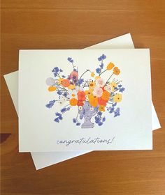 a bouquet of flowers is on top of two cards with congratulations written in the middle