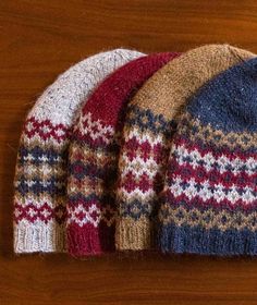 three knitted hats sitting on top of a wooden table