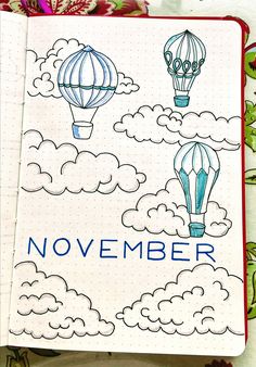 an open notebook with drawings of hot air balloons and the words november written in blue ink