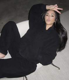 a woman sitting on top of a white chair with her hand up in the air