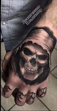 a man's hand with a skull and cross tattoo on the middle of it