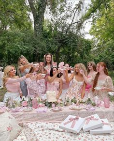 a group of women standing next to each other in front of a table filled with cakes