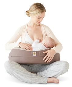 a woman sitting on the floor holding a baby in her arms and looking at it