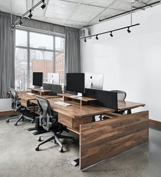 an empty office with desks and chairs in front of a large window overlooking the city