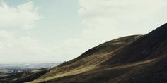 a grassy hill with hills in the background