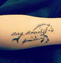 a person with a tattoo on their arm that says stay strong and a horse is running