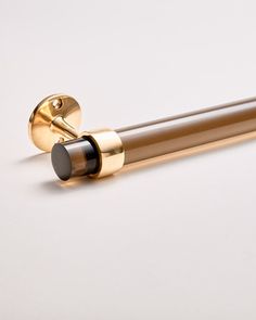 a close up of a metal object on a white surface with a black and gold handle