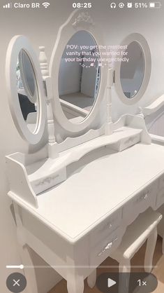 a white vanity with three round mirrors on it