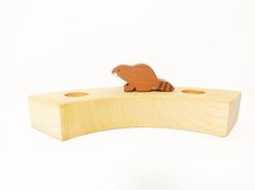 a small wooden animal sitting on top of a piece of wood with holes in it