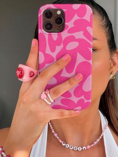 a woman holding her phone up to her face and wearing a pink leopard print case