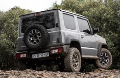 a grey jeep is parked in the woods