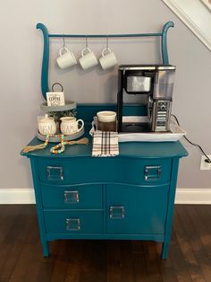 a blue dresser with coffee cups and mugs on it next to an espresso machine