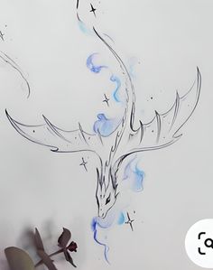 a drawing of a dragon with blue and white paint on it's wings, in front of a wall