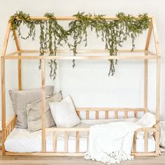 a bed with plants growing over it and pillows on the bottom bunk, in front of a white wall