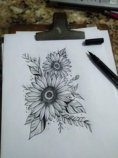 a clipboard with a drawing of a sunflower on it next to a pen