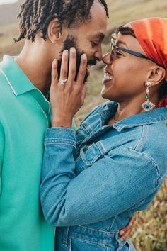 a man and woman standing next to each other with their hands on their faces, smiling