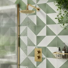 a shower with green and white tiles on the wall next to a toilet in a bathroom