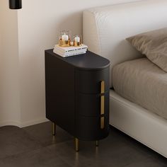 a nightstand with two candles on it next to a bed