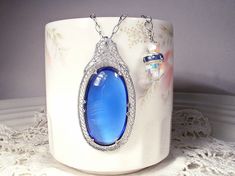 "I am so excited to be offering an exquisite antique Edwardian/Art Deco 1930s era rhodium plated filigree rich sapphire blue glass cabochon pendant necklace. This will be as gorgeous with a pair of jeans and a tee as it will be with a Bridal gown. (The perfect \"Something Old\" and \"Something Blue\".) I can't tell you how much I love this antique treasure! It's designed like a camphor glass necklace of the period but has a an amazing blue cabochon rather than camphor glass center. The pendant f Heirloom Blue Necklaces For Weddings, Blue Art Deco Jewelry For Wedding, Antique Blue Jewelry For Wedding, Vintage Blue Jewelry For Wedding, Antique Blue Wedding Jewelry, Vintage Blue Wedding Jewelry, Blue Filigree Necklace For Wedding, Wedding Something Old, Wedding Something Blue