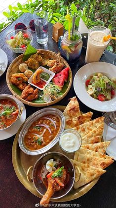 a table topped with lots of plates and bowls filled with different types of food next to drinks