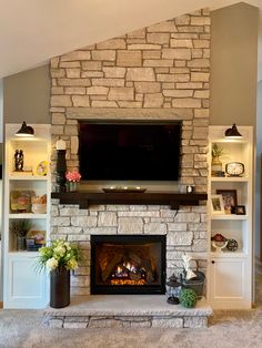 a living room with a stone fireplace and built - in entertainment center on the wall