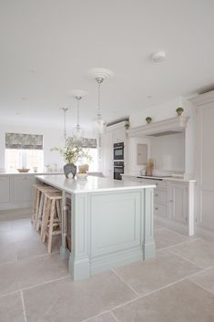 a large kitchen with an island and stools in the center, surrounded by white cabinets