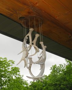 a chandelier made out of antler antlers hanging from the ceiling in front of trees