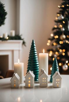 three lit candles sitting on top of a table next to a christmas tree and small houses