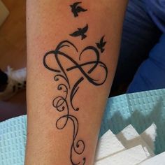 a tattoo on the arm of a woman with birds flying around her and an intertwined heart