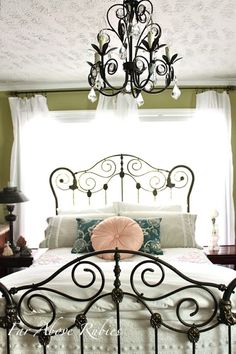 a bedroom with green walls, white bedding and a chandelier hanging from the ceiling