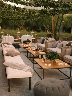 an outdoor seating area with couches, tables and candles on the tables in front of them