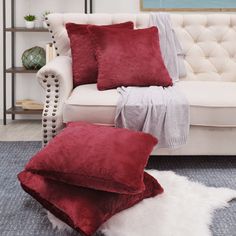 a living room with a white couch, red pillows and a rug on the floor