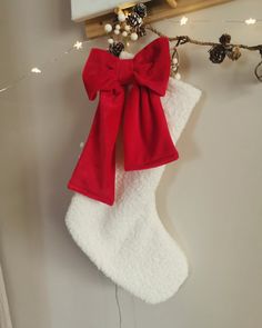 a christmas stocking hanging on the wall with a red bow and ribbon attached to it