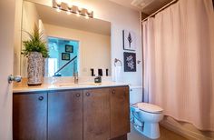 a white toilet sitting next to a bathroom sink under a mirror above a wooden cabinet