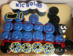 a birthday cake decorated like a train with cupcakes