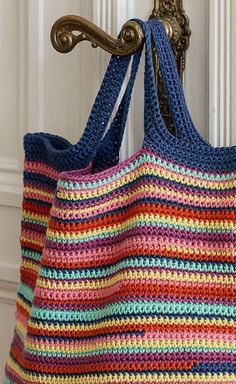 a multicolored crocheted bag hanging from a hook on a door handle