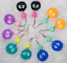 a bunch of different colored earrings with eyes and stars on them, arranged in a circle